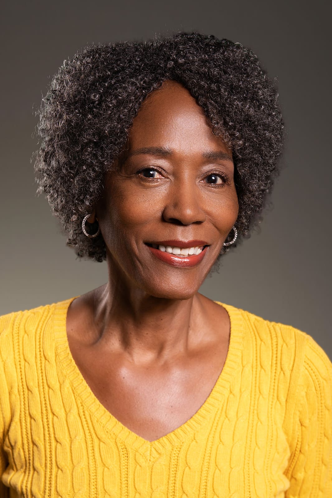 Portrait of Armanda smiling gently in a yellow sweater, photographed in Minneapolis studio lighting for professional modeling headshots by Dahli Durley.