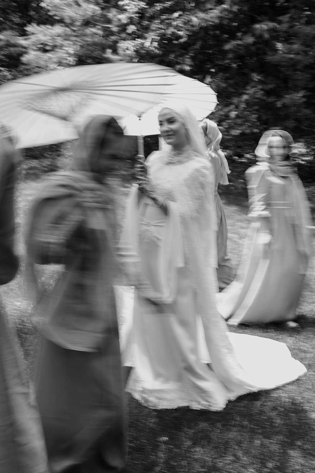 Bride walks with loved ones under a parasol during a Muslim wedding at The Glass Haus in Minneapolis, photographed by Dahli Durley.
