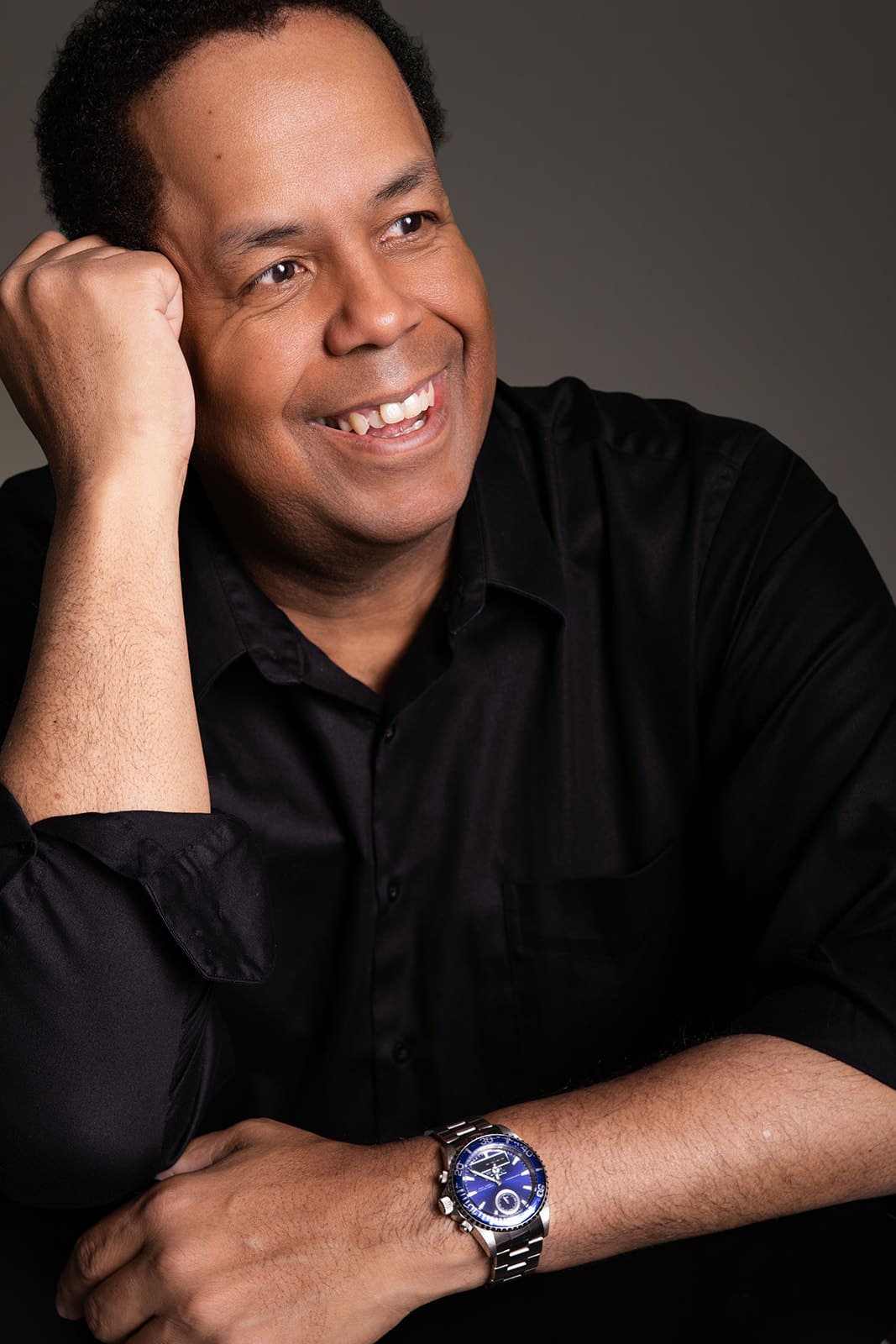 Roderick Collins smiling in a black shirt and silver watch, photographed in Minneapolis studio lighting for professional modeling headshots.