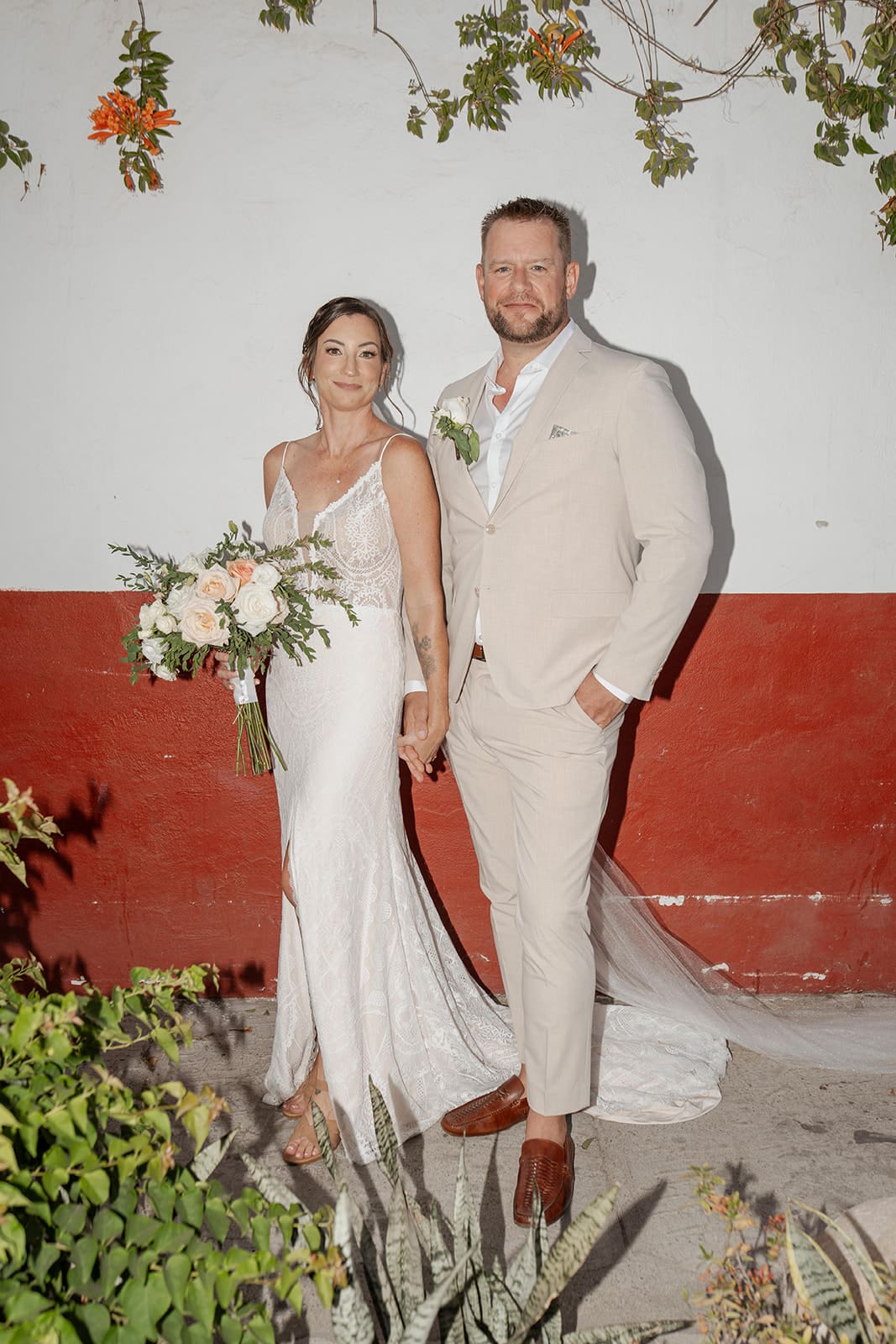 Bride and groom standing against a red and white wall during their Puerto Vallarta destination wedding.